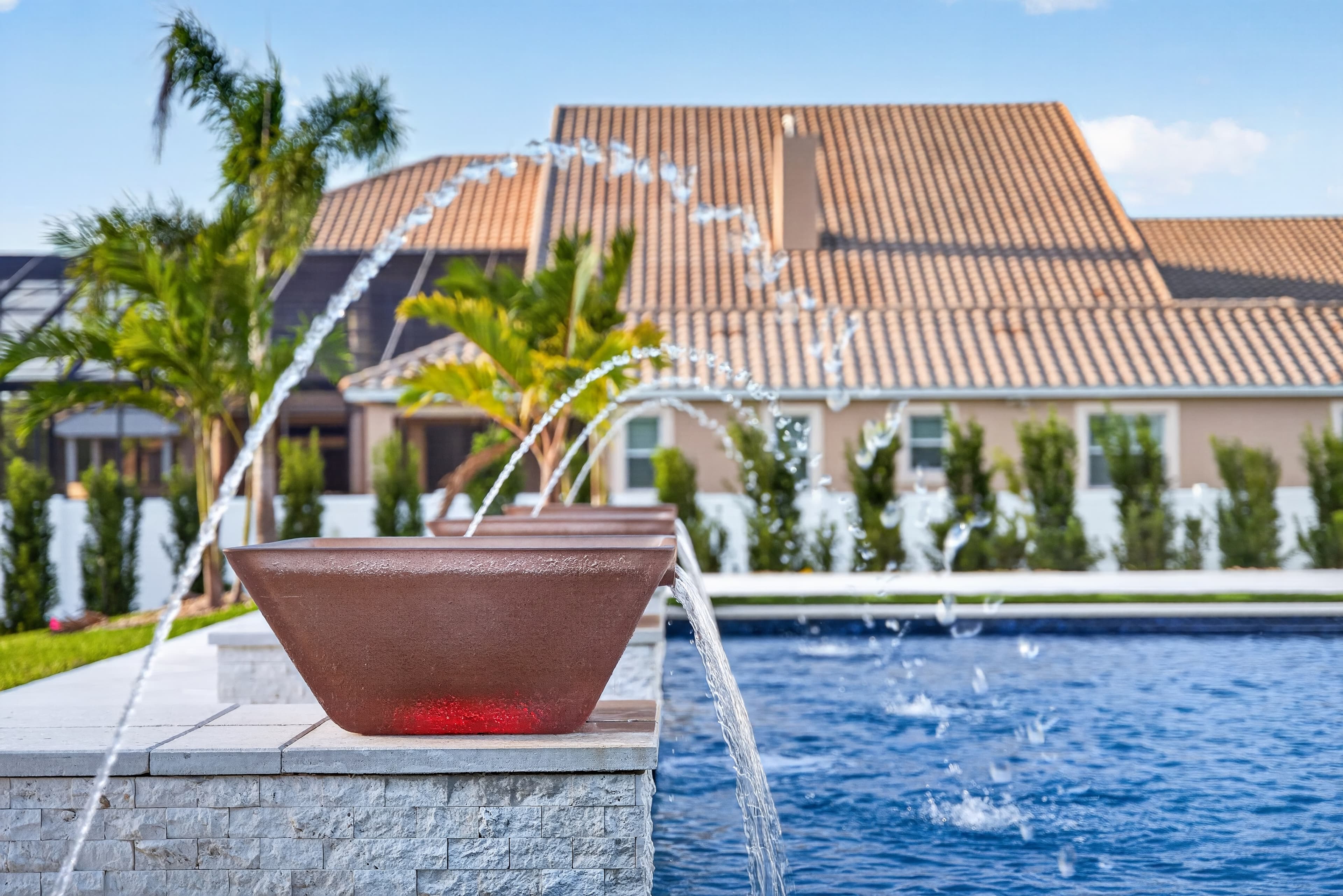 Pool deck-jet detail with the home softened in the background under a clear sky